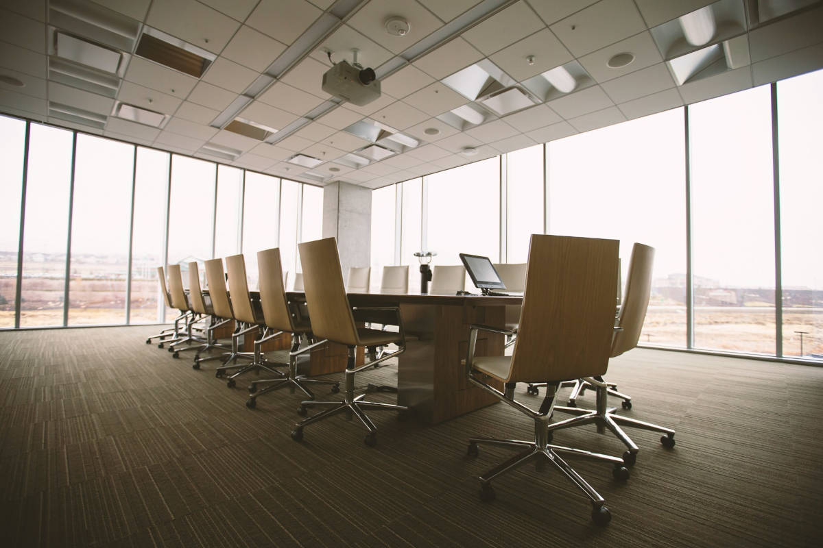 A large meeting room table surrounded by chairs and large windows